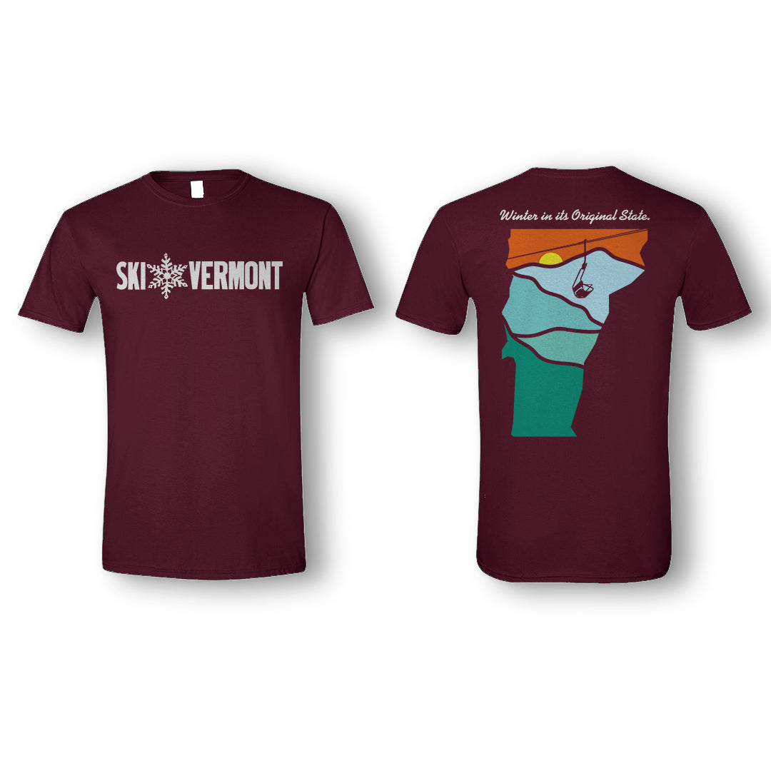 Front and back of a maroon “Ski Vermont” T-shirt. The front displays the Ski Vermont logo in white, with a snowflake graphic between “Ski” and “Vermont.” The back features a stylized outline of Vermont filled with layered landscape colors—green, blue, and orange—depicting mountains, a sunset, and a ski lift. Above the design, white text reads “Winter in its Original State.”